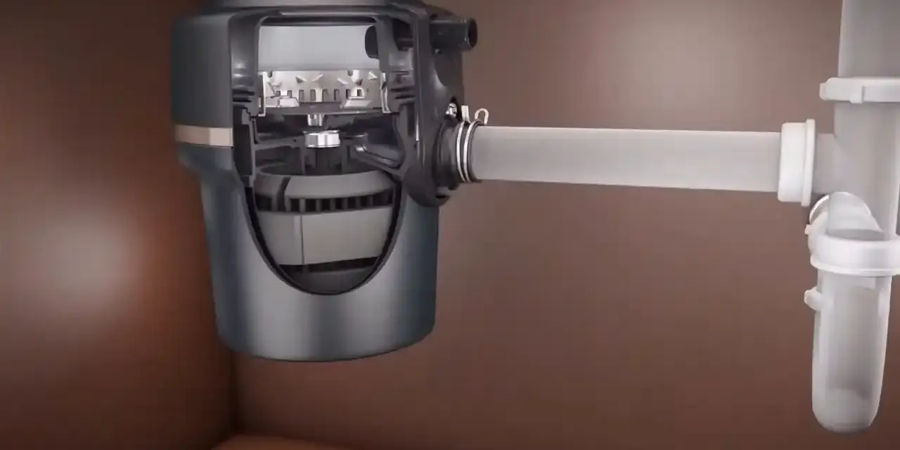 Garbage disposal mounted under a kitchen sink with drain connections